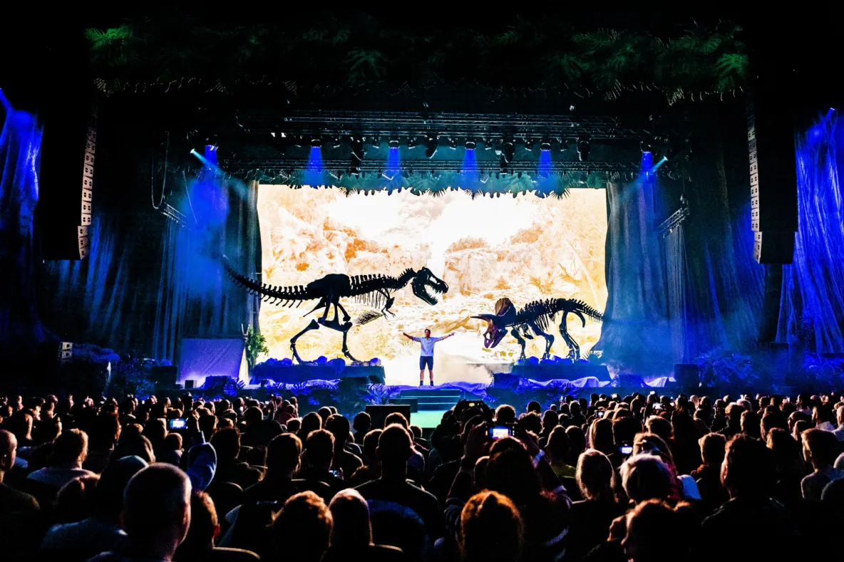 Freek Vonk op het podium met T. rex en Triceratops