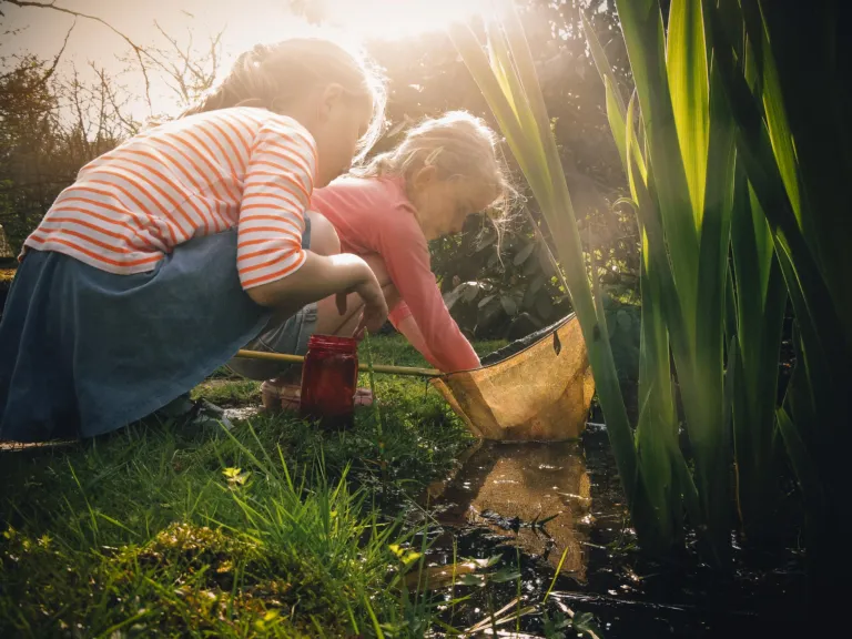 2 kinderen zoeken naar dieren in een vijvertje